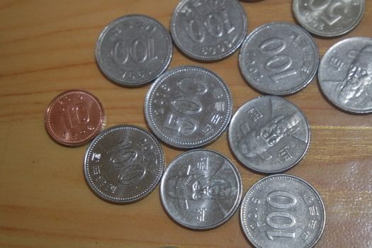 Silver shining Korean won coin scattered over a wooden floor.