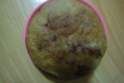 Closeup view of homemade tasty potato bread rolls bun placed in a pink plastic plate over wooden floor.