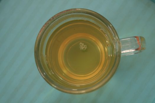 Glass cup having brewed fragrant green tea or qehwa or qahwa on the wooden floor. It is served with sugar or honey and nuts