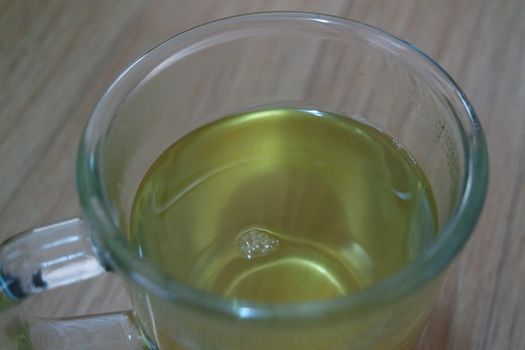 Glass cup having brewed fragrant green tea or qehwa or qahwa on the wooden floor. It is served with sugar or honey and nuts