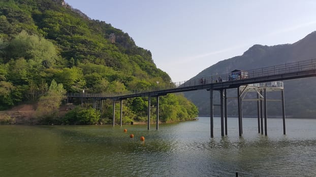 View of beautiful scene of river water and green trees on large hills on a sunny day with blue sky in background. A lovely landscape with breathtaking view over the horizon .