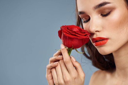 woman with a rose in her hands naked shoulders evening makeup red lips. High quality photo