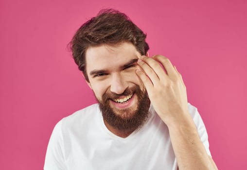 Handsome man with a beard and mustache on a pink background in a white T-shirt. High quality photo