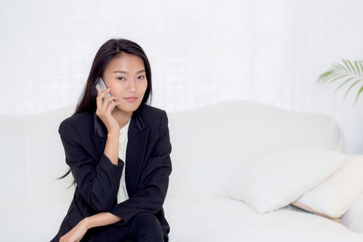 Beautiful young asian woman talking phone and smile in the living room, businesswoman sitting on sofa,businesswoman calling telephone, communication concept.