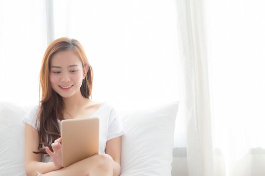 Portrait of beautiful asian young woman with holding and reading digital tablet computer with leisure, girl using tablet with relax at bedroom, lifestyle and communication concept.