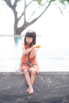 Beautiful portrait little girl asian of a smiling standing at swimming pool, kid leisure and joyful in outdoor.