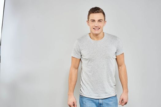 Cheerful emotional man gray t-shirt gesturing with hands studio lifestyle. High quality photo