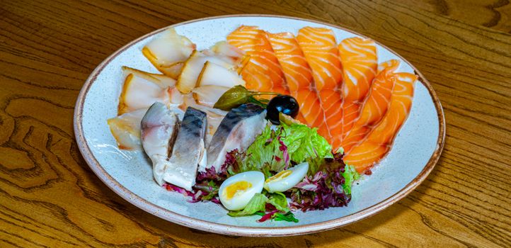 Dishes of herring, mackerel and red fish on a plate seasoned with quail egg and salad