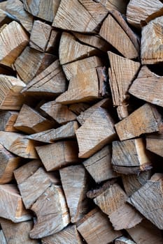 Firewood is stacked one on top of the other. Background texture. Vertical photo.