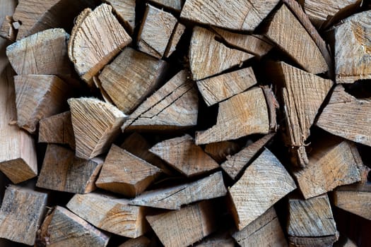 Firewood is stacked one on top of the other. Background texture. Vertical photo.