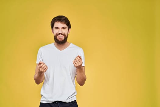 Man gesturing with hands emotions lifestyle white t-shirt yellow isolated background. High quality photo