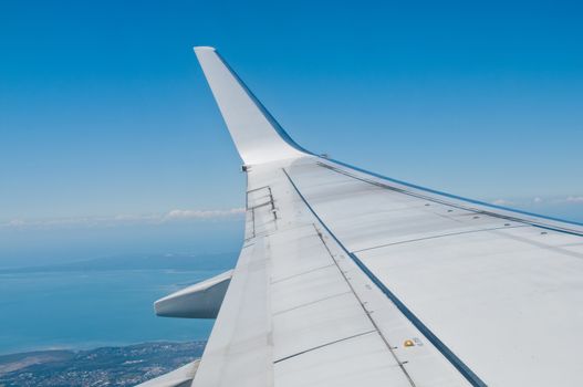 White silver plane wing flying in blue sky