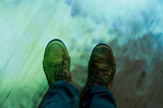 Brown leather shoes and blue jeans standing on a colourful floor