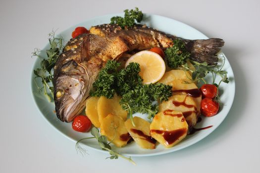 Close-up of fried fish and potatoes decorated with a slice of lemon.Texture or background