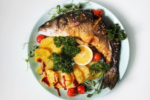 Close-up of fried fish decorated with a slice of lemon and cherry tomatoes .Texture or background