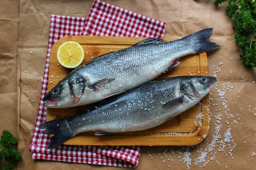 Raw fish on a cutting Board decorated with a slice of lemon close up.Texture or background