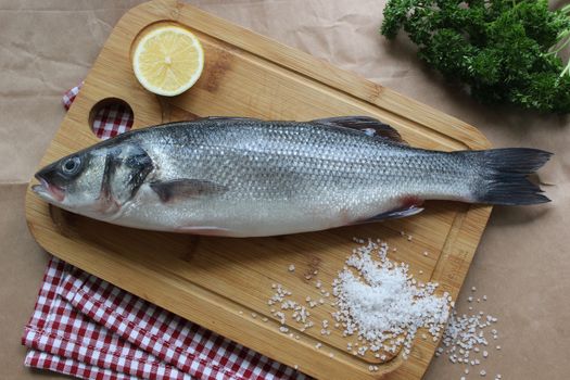 Raw fish on a chopping Board close-up with a slice of lemon.Texture or background