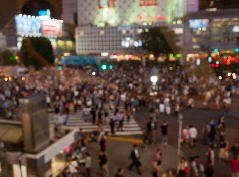 Defocused night scene of people crossing Shibuya intersection in Tokyo Japan