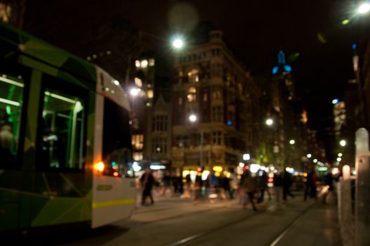 Defocused scene of people walking with tram at night in busy city in Winter