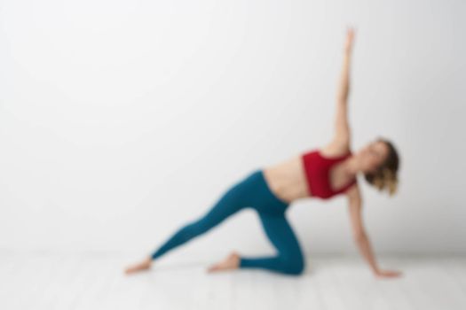 A woman in blue jeans practices yoga on a light background indoors and a slim figure in gymnastics. High quality photo