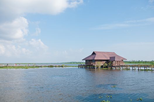 Thai traditional teakwood village in blue calm lake