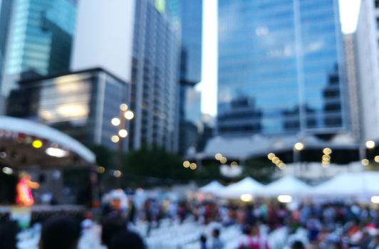 Defocused scene of crowd of people attending public concert celebrating New Year festival in city in Evening