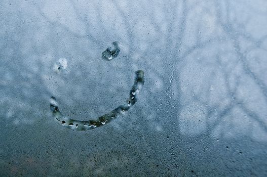 Smiley shape on droplet window of cold misty morning