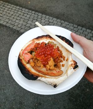 Grilled giant Hokkaido scallop takeaway with chopsticks and right hand