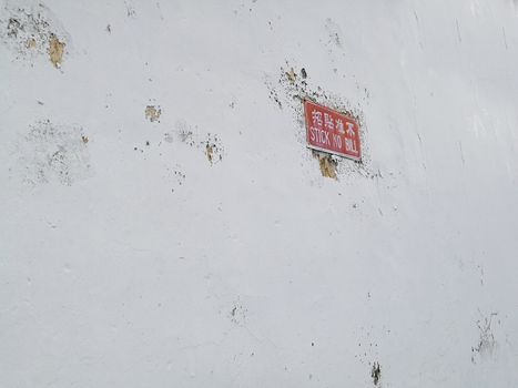 White concrete wall with red stick no bill post sign