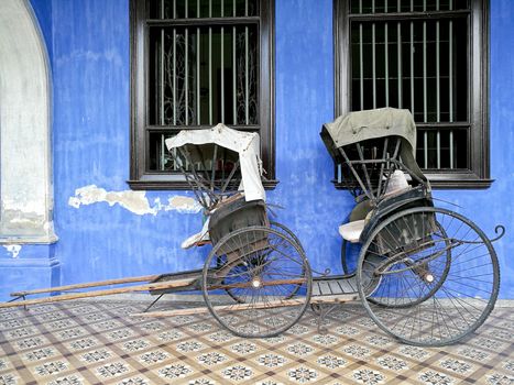 Old vintage traditional rickshaws in front of blue building in Penang