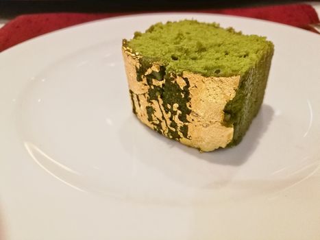 Fluffy matcha green tea with gold flake luxury cake on white plate