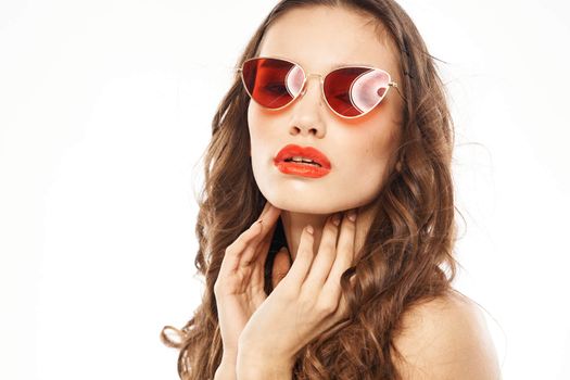 Portrait of brunette woman in sunglasses naked shoulders light background. High quality photo