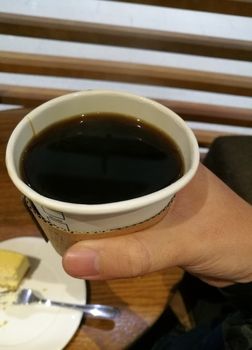 Right hand holding black Americano coffee