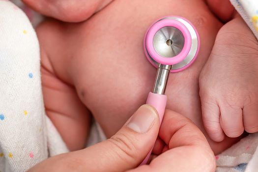 A nurse using a stethoscope to examine a newborn baby's heart