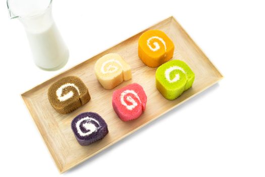 Slices of colorful sweet rolls with creamy filling and a glass of milk. White background.