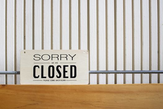 Sorry we're closed sign on an emty wood panel wall. Places temporarily closed during coronavirus pandemic.