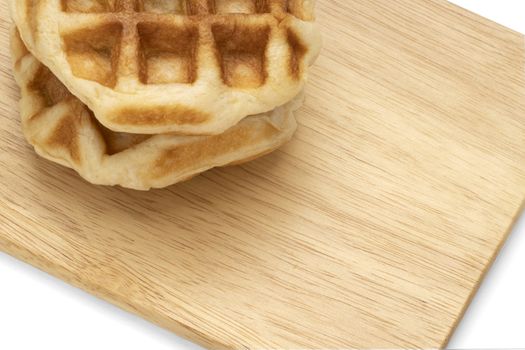 Closeup of fresh waffles on a wooden trey. White background..