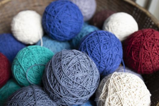 Assortment of natural color dyed cotton balls in a wicker basket.