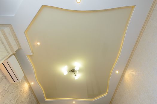 Multi-level stretch ceiling of the original shape in gold color