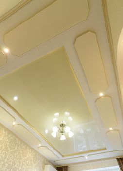 Original stylish multi-level ceiling in gold tones in the bedroom