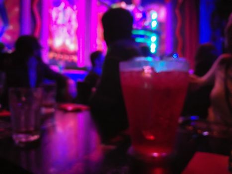 Defocused abstract blurred scene of people enjoy drinking and eating in a dark night club