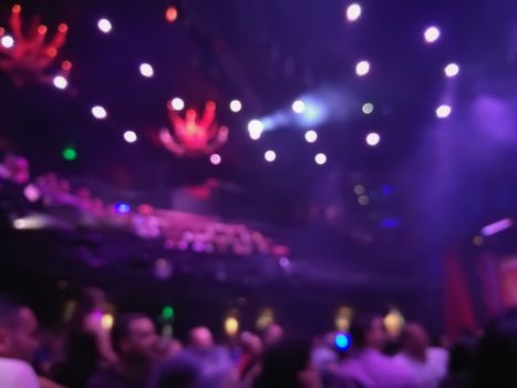 Defocused abstract blurred scene of musical light performance in a concert on stage with crowd