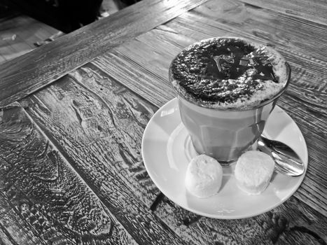 Black and white hot creamy mocca chocolate coffee served on a wooden table with two marshmallow