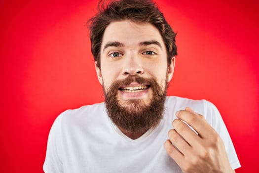 Bearded man fun emotions lifestyle cropped view white t-shirt red background. High quality photo