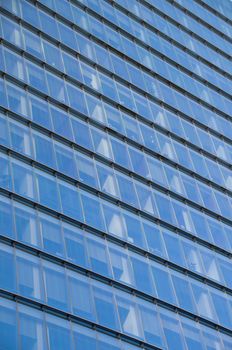 Reflection of blue clear sky on a high-rise skyscraper corporate office building