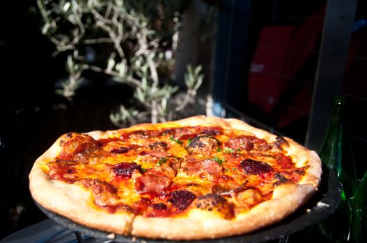 Freshly made Italian Margherita pizza served on a hot plate in a sunny day