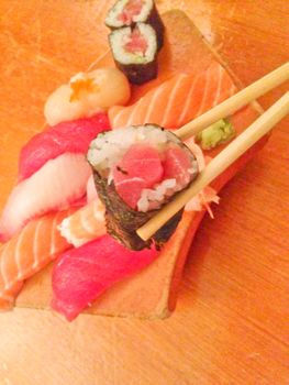 Mixed fresh Japanese sushi platter served on wooden plate and eat with chopsticks