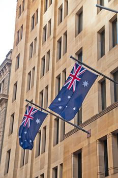 Two Australia flags hanging from a sandstone building