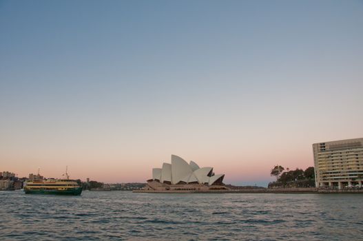 SYDNEY, AUSTRALIA - MAY 5, 2018: Sydney Opera House with famous Sydney city ferry in late afternoon and twililght sky.