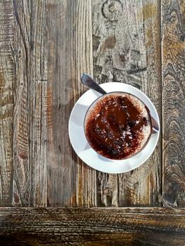 Top view of sweet dark warm hot chocolate on wooden brown table with a spoon